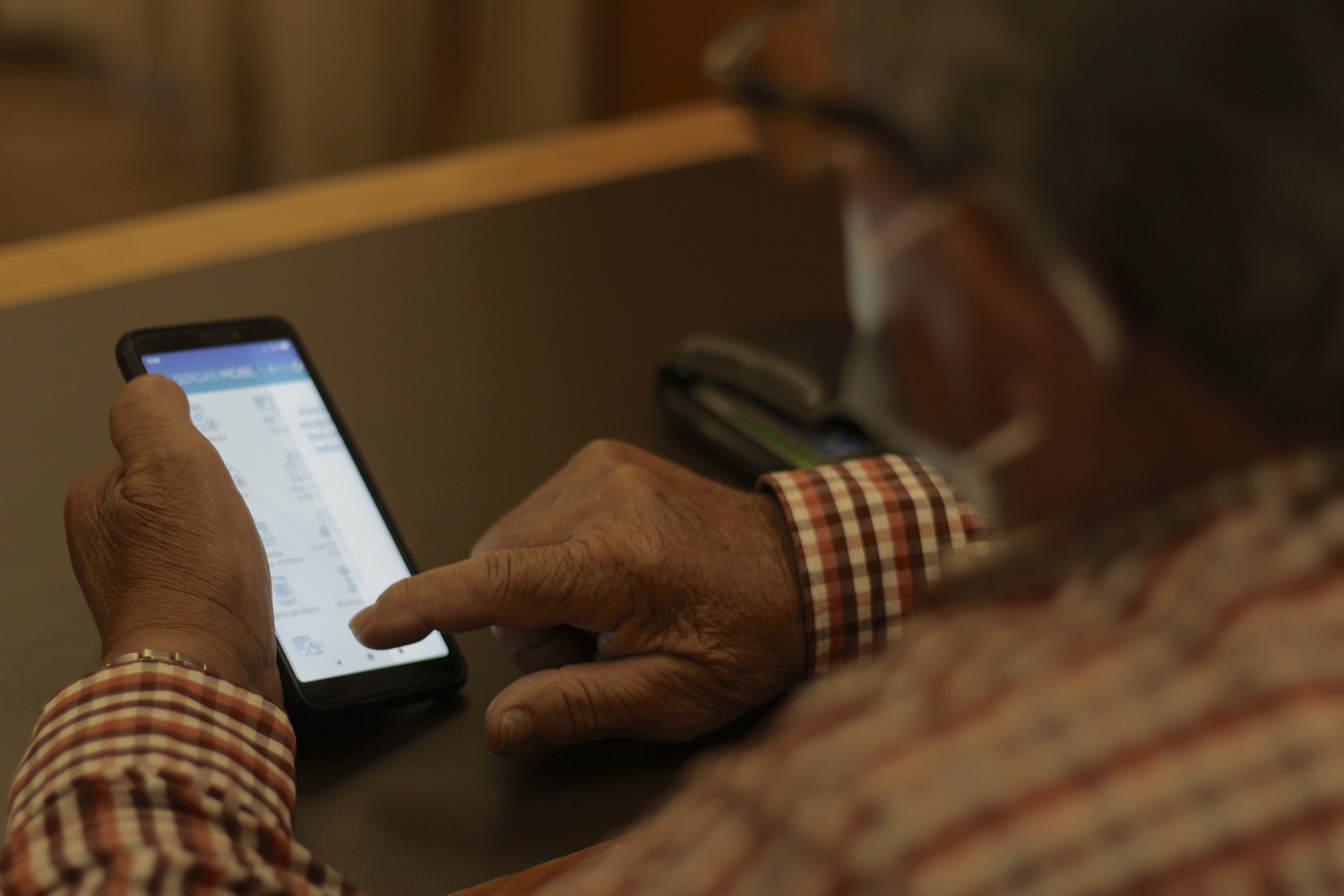Primer plano de unas manos de una persona mayor utilizando un smartphone