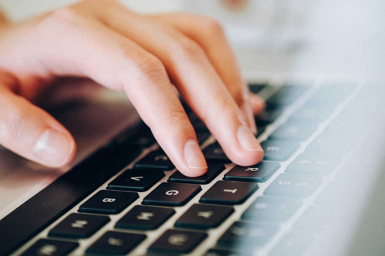 En la imagen aparece una mano escribiendo sobre un teclado de un ordenador.