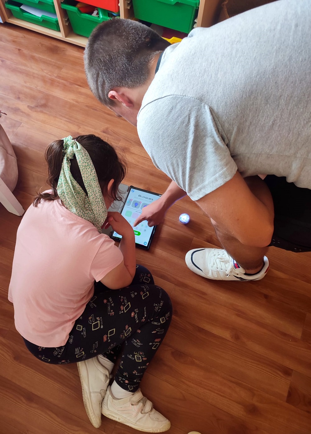 Vemos a 1 niña y 1 niño tocando una tablet para jugar y dar órdenes a la Sphero