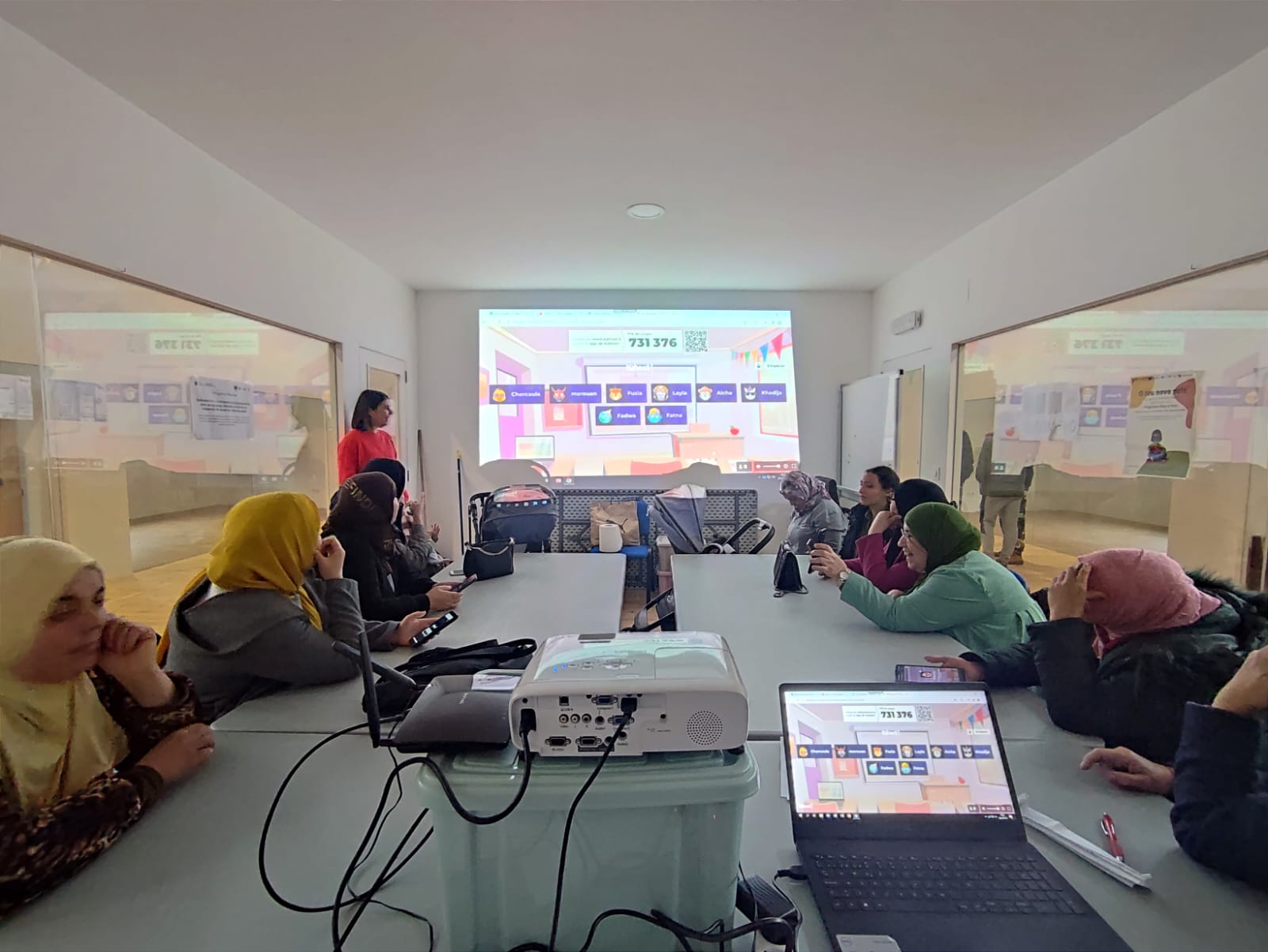 Vemos una foto de aula en el que el grupo de personas migrantes está haciendo una dinámica digital durante el taller.