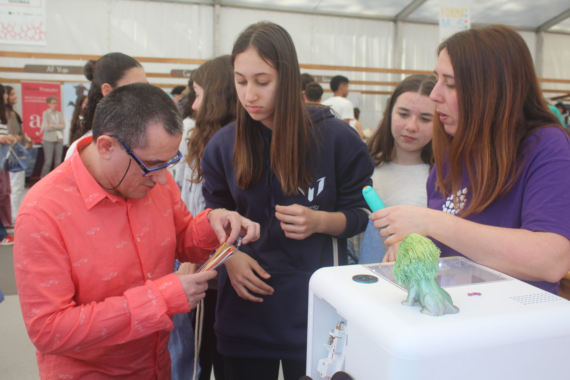 Uno de los usuarios de los talleres participante en la Feria de Educación ayuda a una alumna con las herramientas digitales.