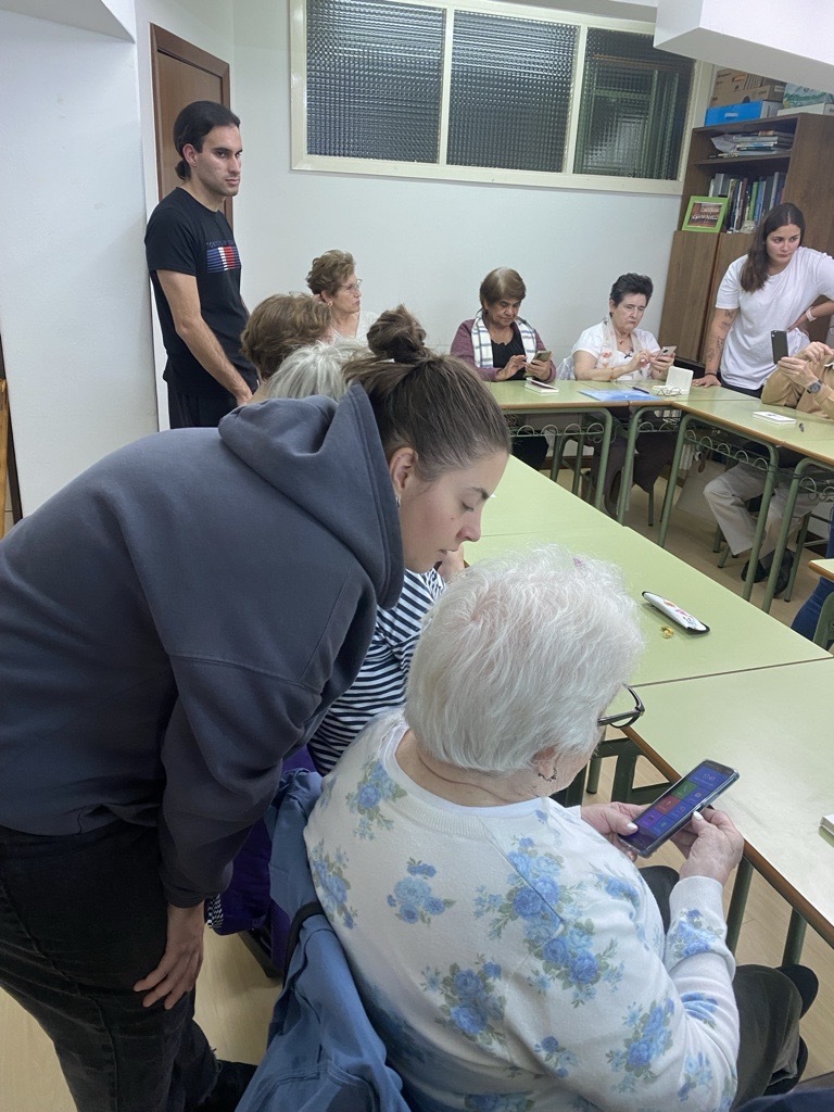 Una de las alumnas del CPR San José de la Guía ayudando a una señora con una duda con su smartphone.